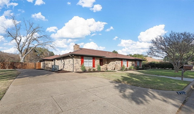 ranch-style house with cooling unit, brick siding, driveway, a chimney, and a front yard