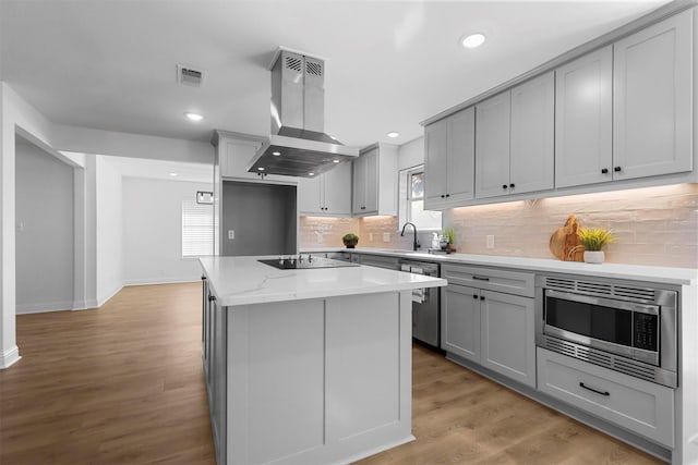 kitchen with stainless steel appliances, gray cabinets, visible vents, and island range hood