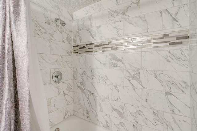 bathroom featuring tiled shower / bath combo and a textured ceiling