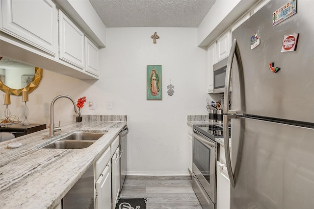 kitchen with white cabinetry, appliances with stainless steel finishes, sink, and a textured ceiling