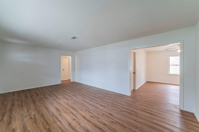 unfurnished room featuring a textured ceiling and dark hardwood / wood-style flooring