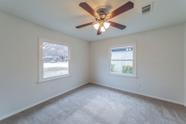 carpeted spare room featuring ceiling fan and plenty of natural light