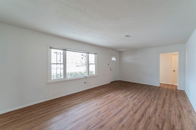 spare room featuring wood-type flooring and a textured ceiling