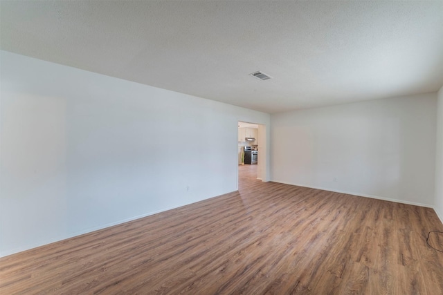 unfurnished room with hardwood / wood-style flooring and a textured ceiling