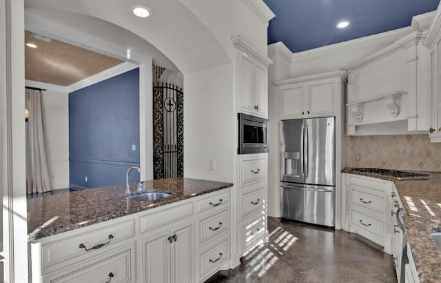 kitchen featuring appliances with stainless steel finishes, tasteful backsplash, white cabinetry, sink, and dark stone countertops