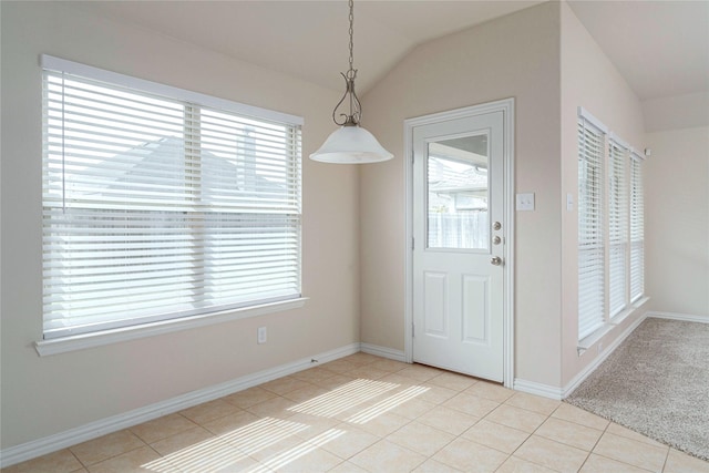 unfurnished dining area with lofted ceiling and light tile patterned floors