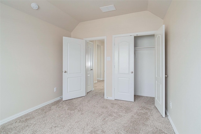 unfurnished bedroom with lofted ceiling, light colored carpet, and a closet