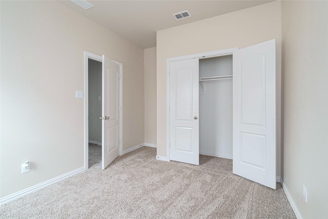 unfurnished bedroom with light colored carpet and a closet