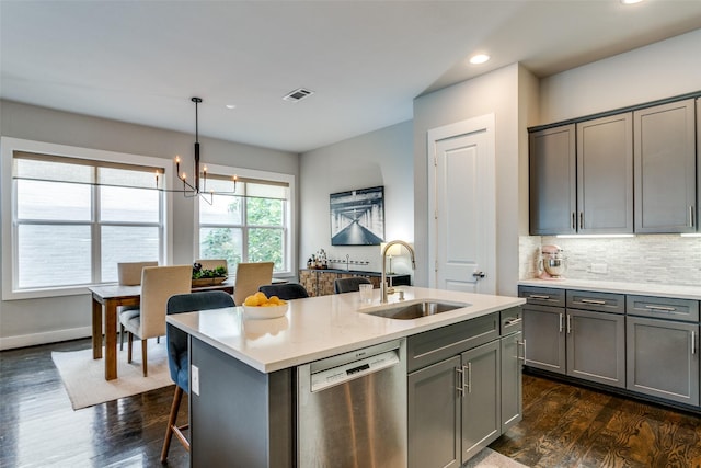 kitchen with sink, gray cabinets, a center island with sink, decorative light fixtures, and stainless steel dishwasher