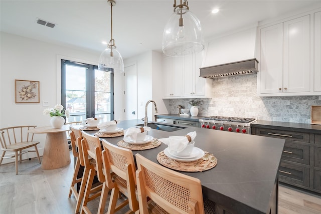 kitchen featuring tasteful backsplash, white cabinetry, sink, and pendant lighting