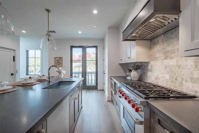 kitchen featuring sink, white cabinetry, decorative light fixtures, custom range hood, and range with two ovens