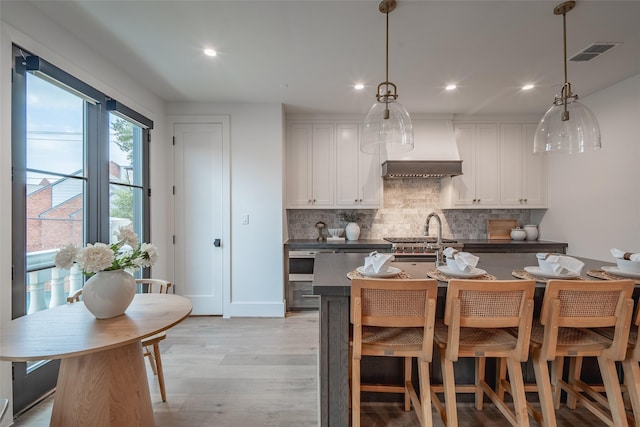 kitchen featuring hanging light fixtures, white cabinets, and light hardwood / wood-style flooring