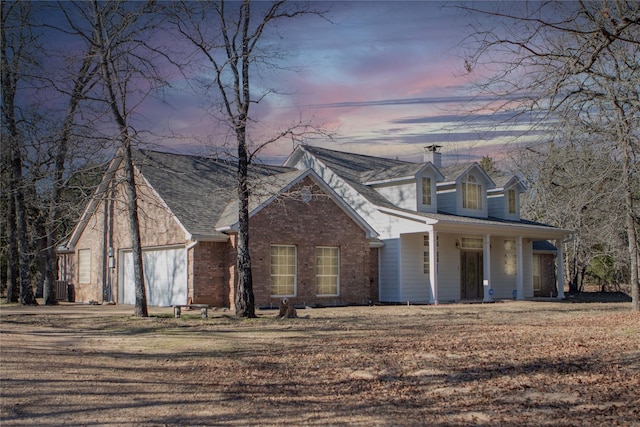 cape cod-style house featuring a garage, covered porch, and central air condition unit