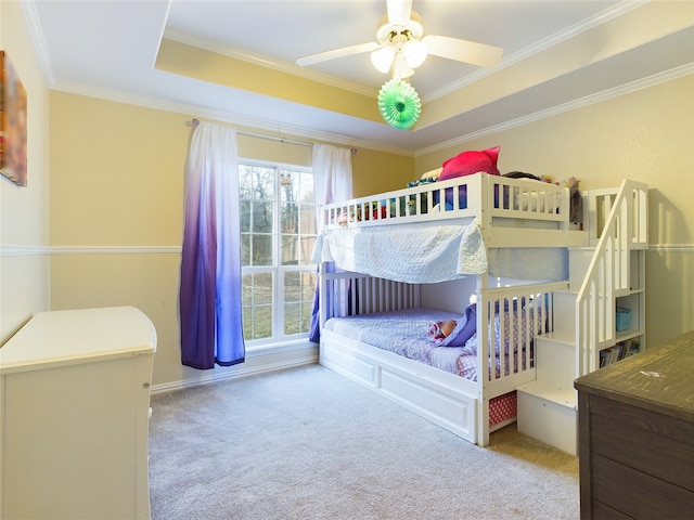 bedroom featuring crown molding, light carpet, ceiling fan, and a tray ceiling