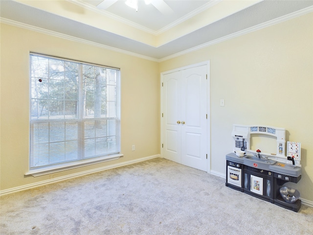 interior space with crown molding, light colored carpet, a raised ceiling, and ceiling fan