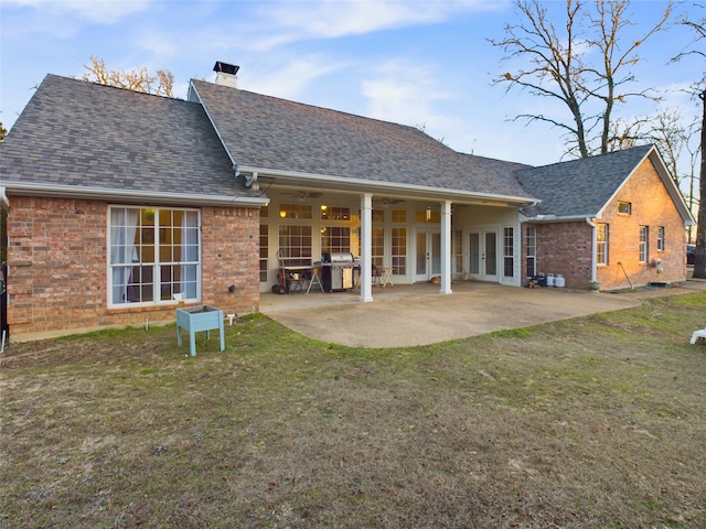 rear view of property with a patio and a lawn