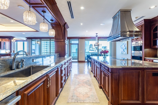 kitchen featuring a spacious island, sink, decorative light fixtures, a notable chandelier, and island exhaust hood