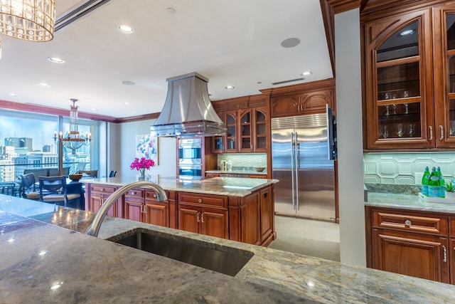 kitchen with sink, stainless steel appliances, light stone countertops, decorative light fixtures, and a chandelier