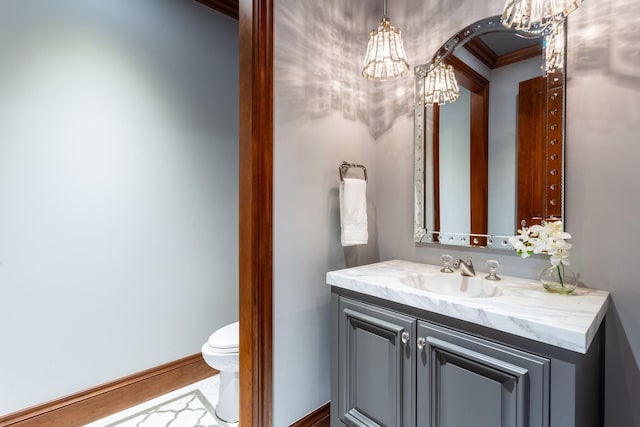 bathroom with vanity, ornamental molding, toilet, and an inviting chandelier