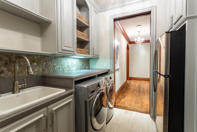 laundry area with sink, light hardwood / wood-style flooring, cabinets, independent washer and dryer, and ornamental molding