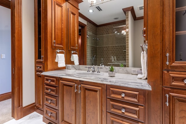 bathroom with vanity, crown molding, and tiled shower