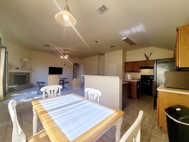 dining space featuring ceiling fan, lofted ceiling, and a fireplace