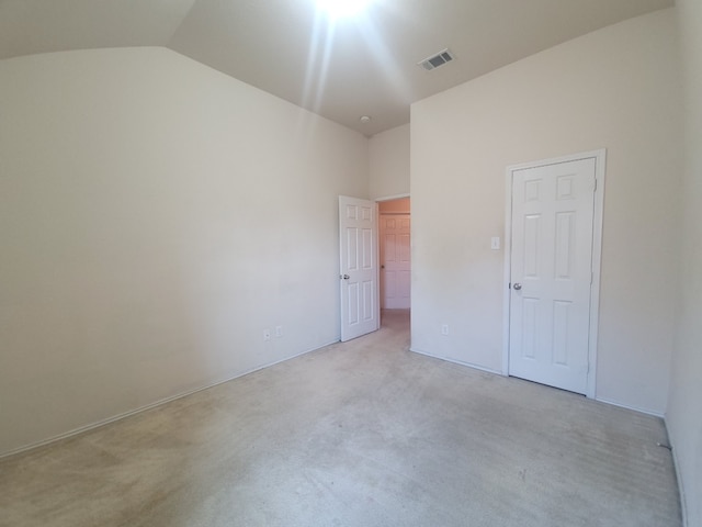 empty room featuring vaulted ceiling and light colored carpet