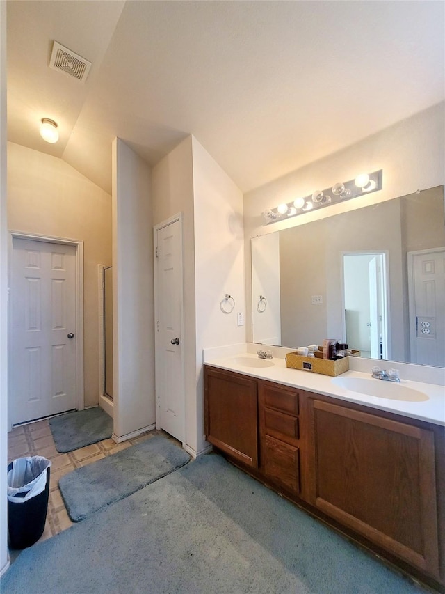 bathroom with lofted ceiling, vanity, and a shower with door