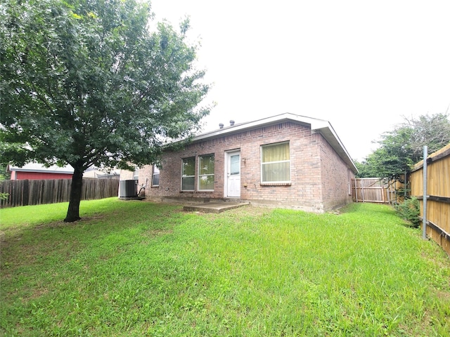 rear view of house with cooling unit and a yard