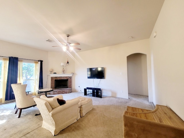 living room featuring a brick fireplace, light carpet, and ceiling fan