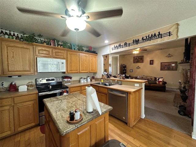 kitchen featuring sink, a kitchen island, kitchen peninsula, and appliances with stainless steel finishes