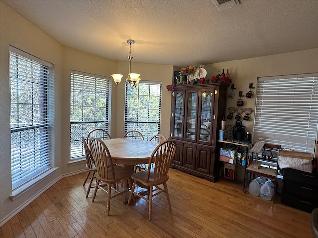 dining space with hardwood / wood-style floors, a textured ceiling, and a notable chandelier