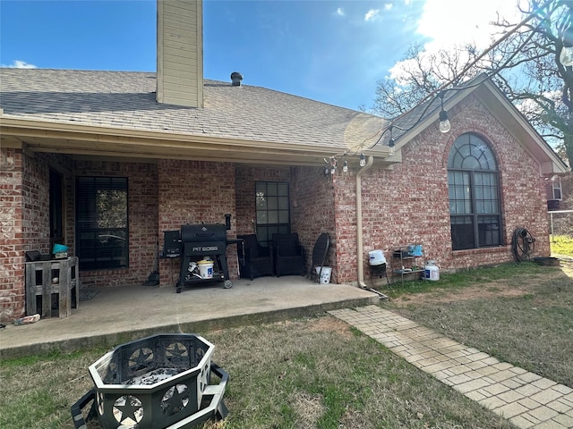 rear view of property featuring a patio, a yard, and an outdoor fire pit