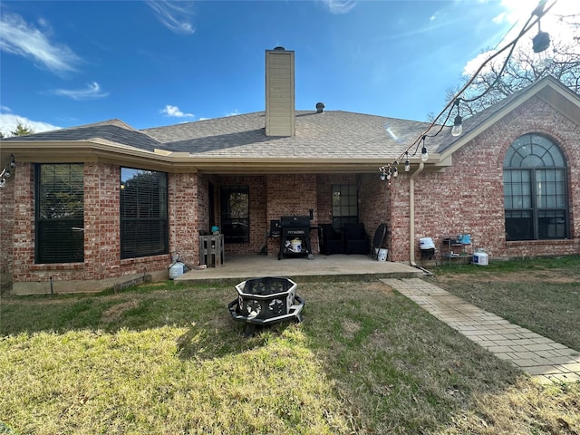 rear view of property with an outdoor fire pit, a yard, and a patio area