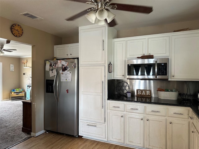 kitchen with stainless steel appliances, light carpet, white cabinets, and ceiling fan