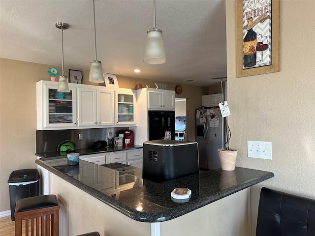 kitchen featuring white cabinetry, a kitchen breakfast bar, hanging light fixtures, kitchen peninsula, and stainless steel refrigerator with ice dispenser