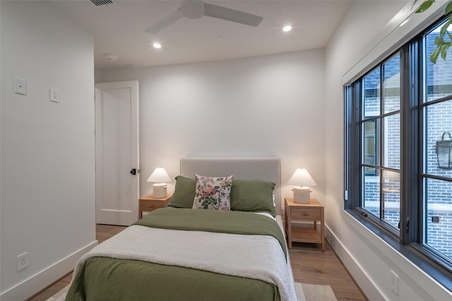 bedroom with multiple windows, hardwood / wood-style floors, and ceiling fan