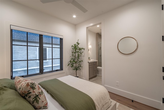 bedroom with light wood-type flooring, ceiling fan, and ensuite bathroom