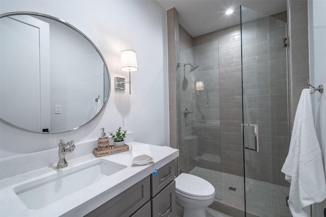 bathroom featuring vanity, a shower with door, and toilet