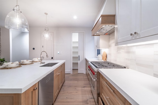 kitchen featuring pendant lighting, sink, appliances with stainless steel finishes, a center island with sink, and decorative backsplash