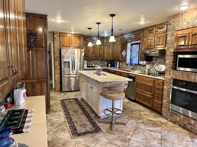 kitchen featuring pendant lighting, a kitchen island, stainless steel appliances, light stone counters, and a kitchen bar