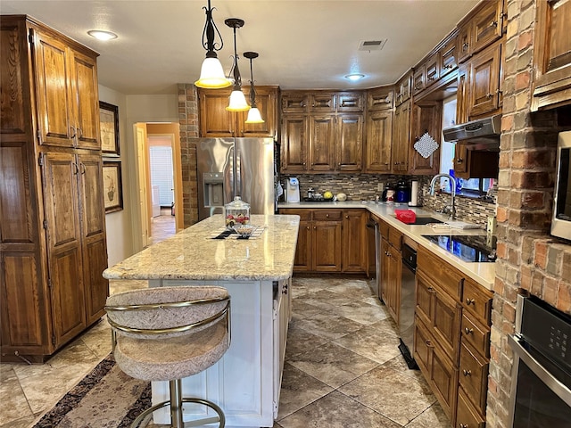 kitchen featuring a kitchen island, appliances with stainless steel finishes, a breakfast bar, sink, and backsplash