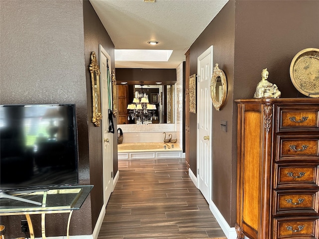 hallway featuring dark hardwood / wood-style floors, a skylight, and a textured ceiling