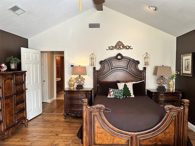 bedroom with lofted ceiling, wood-type flooring, and a textured ceiling