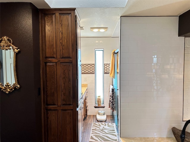 bathroom featuring hardwood / wood-style flooring, vanity, a shower, and a textured ceiling