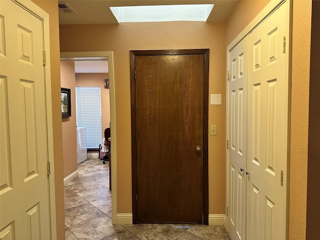 corridor featuring light tile patterned flooring and a skylight