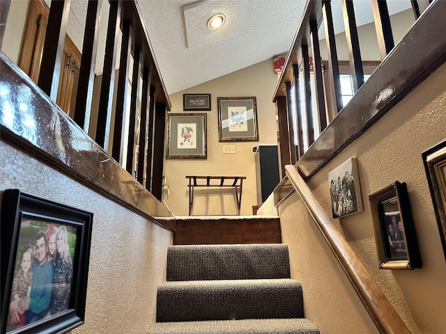 stairs with lofted ceiling and a textured ceiling