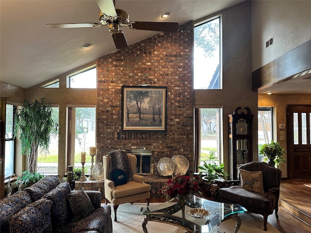 living room featuring ceiling fan, hardwood / wood-style floors, high vaulted ceiling, and a brick fireplace