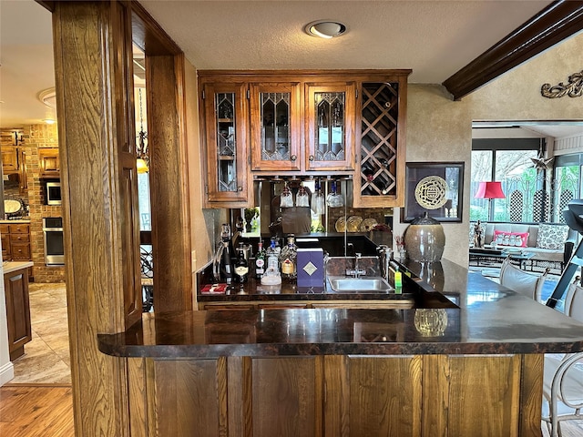 bar with sink, a textured ceiling, ornamental molding, and stainless steel oven