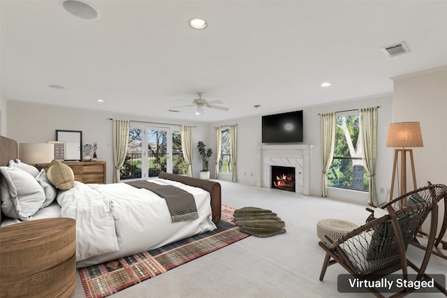 carpeted bedroom with ceiling fan and a fireplace